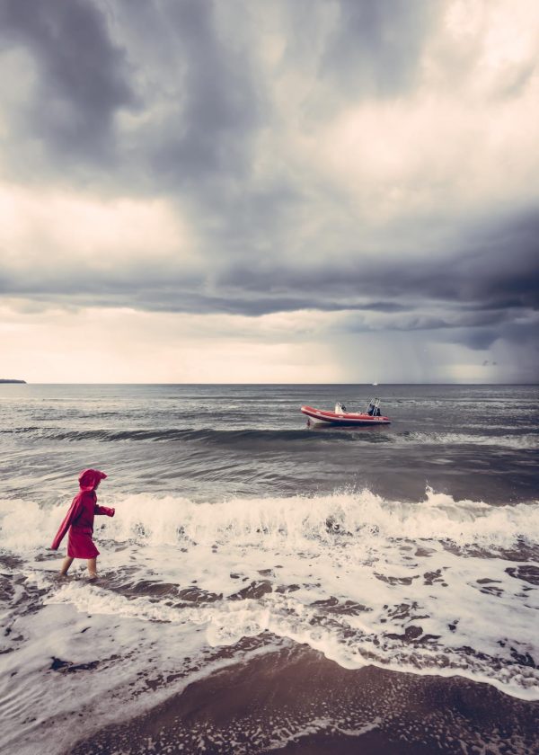 Strandszene mit Mädchen im roten Regenmantel am dänischem Ostseestrand.