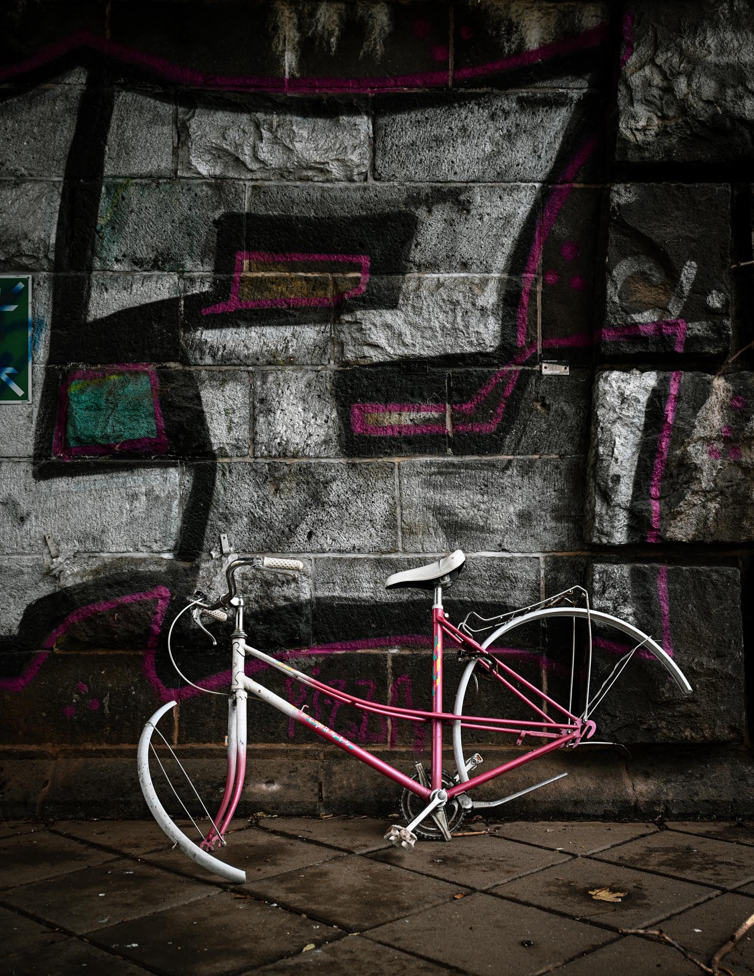 geplünderter Fahrradrahmen vor einer symbolischen Graffiti-Wand mit einer großen gesprayten 2